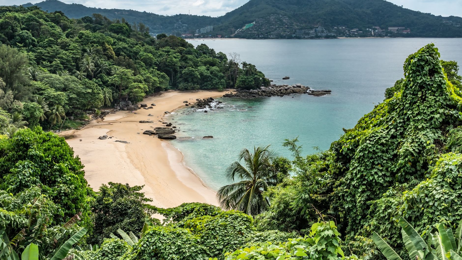 A sandy bay with turquoise water seen through dense tropical forest on a Thai island (illustrative stock photo)